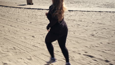 Independent-woman-running-on-the-sand-sunny-beach-of-Santa-Monica-in-California
