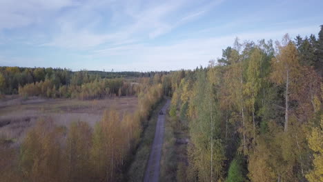 Aerial,-old-tractor-driving-on-autumn-forest-road-in-deserted-rural-area-far-from-civilisation-in-Russia