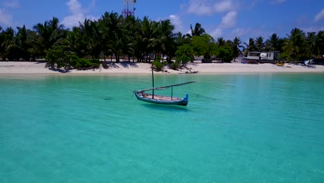 small-wooden-sailing-boat-anchored-at-the-turquoise-shallow-waters-of-a-tropical-island