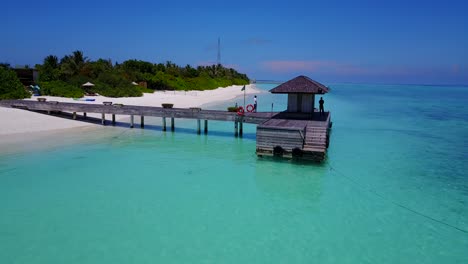 Nahaufnahme-Des-Holzdecks-Auf-Dem-Türkisfarbenen-Meer-Auf-Den-Malediven,-Während-Ein-Personal-Darauf-Wartet,-Dass-Ein-Boot-An-Bord-Geht,-Drohnenaufnahmen