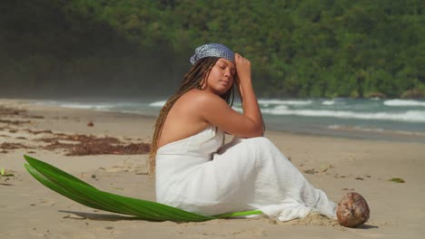 Close-up-slow-motion-of-a-young-woman-in-a-beach-dress-sitting-on-the-beach-on-a-tropical-island
