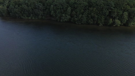 Aerial-drone-ascending-pov-over-Trémelin-over-lake-and-green-forest,-Brittany-in-France