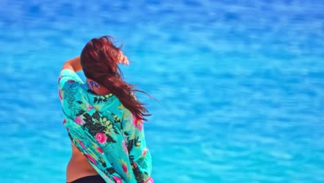 Girl-looks-horizon-on-windy-beach,-blue-sea-background