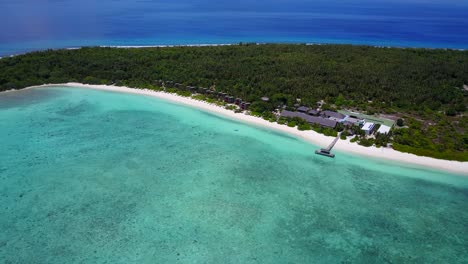 Perfect-summer-day-on-Hanimaadhoo-island-in-the-Maldives,-high-aerial-view-of-beach-bungalows-hidden-in-the-tropical-jungle