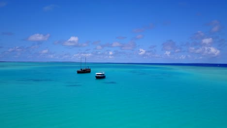Luftaufnahme-Von-Zwei-Touristischen-Booten,-Die-Auf-Einer-Tropischen-Insel-Mit-Palmen-Verankert-Sind-Und-An-Einem-Klaren-Tag-Zoomen