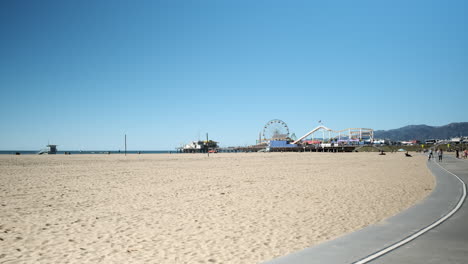 Carnival-funfair-distant-on-the-sandy-beach-of-Santa-Monica-California,-on-a-sunny-day