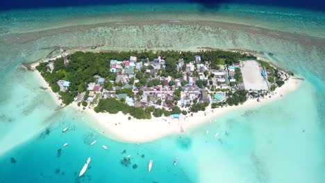 Vista-A-Gran-Altura-De-Un-Resort-En-Las-Maldivas-Con-Un-Atolón-Y-El-Mar-Que-Va-De-Turquesa-A-Azul-Profundo