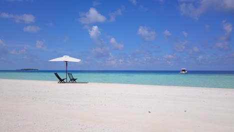 a-slow-circular-slider-move-on-the-white-beaches-of-the-turquoise-Caribbean-sea,-with-two-empty-wooden-seats-under-a-white-parasol