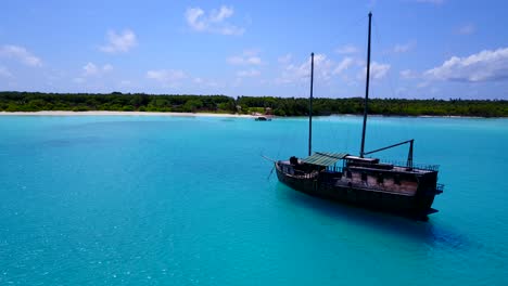 a-touristic-boat-anchored-at-the-turquoise-waters-of-a-tropical-island,-drone-footage