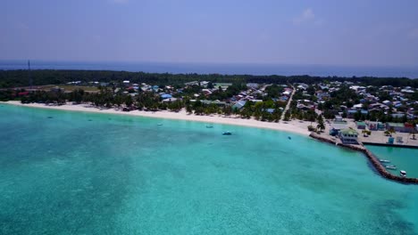 a-view-of-a-resort-hotel-and-its-wood-deck-on-the-turquoise-sea-in-the-Maldives,-drone-footage