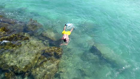 Man-snorkeling-in-Maldives-crystal-clear-waters,-close-aerial-pan-4k