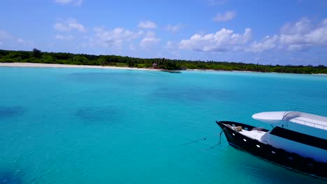 aerial-view-of-a-power-boat-anchored-close-to-a-Caribbean-island-with-a-white-sandy-beach-and-turquoise-water