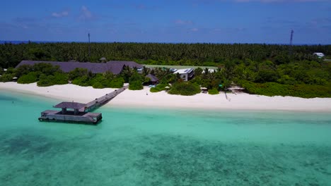 Exclusive-Maldives-resort,-pan-left-over-wooden-pier-and-swimming-beach-4k