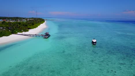 a-view-of-a-resort-hotel-and-its-wood-deck-on-the-turquoise-sea-in-the-Maldives,-drone-footage-with-camera-tilt-motion-on-a-clear-day
