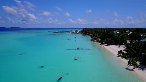 Aerial-rise,-old-fashioned-Dhoni-boats-in-brilliant-aquamarine-waters-of-secluded-Maldives-island,-4k-shot