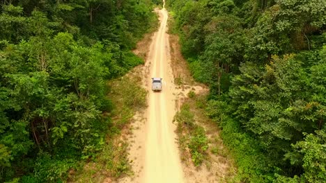 Drone-follows-a-pick-up-truck-travelling-down-a-dirt-road-in-the-Amazon-rainforest