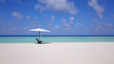 Chair-in-shade-under-parasol-in-Maldives-on-deserted-sand-bar,-slow-panning-shot