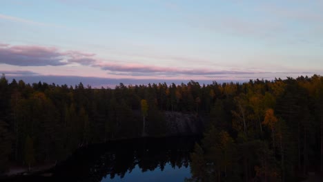 Aerial-view-over-a-tranquil-forest-lake-on-a-sunny-fall-evening-in-Scandinavia