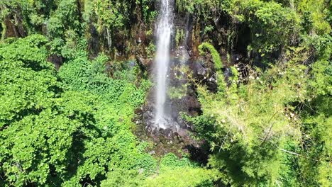 Close-up-shot-of-a-tropical-waterfall-streaming-out-the-lush-green-jungle-AERIAL