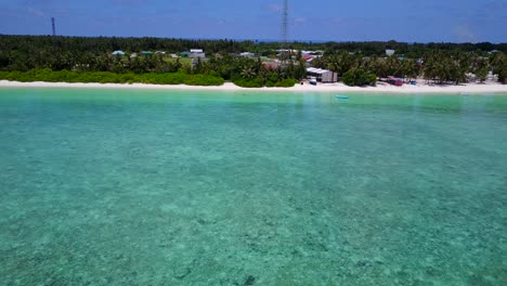 Wide-aerial-movement-along-Maldives-coast-showing-beautiful-beach,-turquoise-water-and-village
