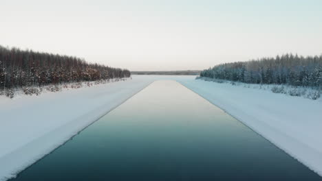 Aerial,-drone-shot,-rising-over-a-iceless-spot,-on-a-river,-on-a-sunny,-winter-day,-in-Utra,-Joensuu,-North-Karelia,-Finland