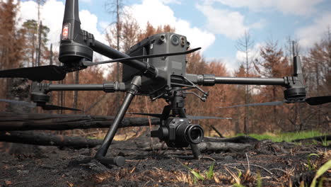 DJI-Matrice-Quadcopter-Drone-With-Camera-in-Burnt-Ground-of-Forest,-Close-Up
