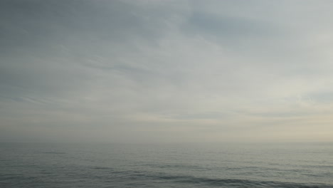 Onduladas-Olas-De-Agua-Oceánica-De-Malibu,-En-Un-Aburrido-Día-Nublado-Por-La-Noche-Con-Nubes-Pasajeras