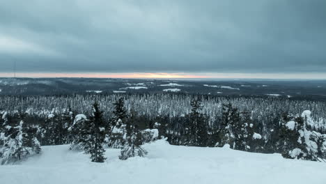 Time-lapse-shot,-of-dark-clouds-moving-over-snow,-covered-trees,-hills-and-nordic-wilderness,-sunset-colors-in-the-background,-on-a-winter-evening,-in-Koli-national-park,-North-Karelia,-Finland