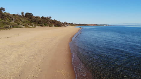 Drone-flight-along-the-golden-sandy-beach-and-blue-ocean-shoreline-of-Sandringham,-Melbourne