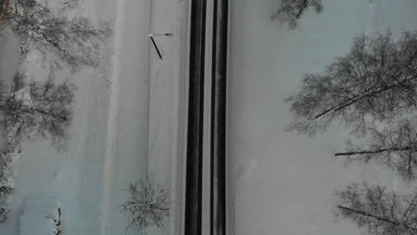 Antenne,-Von-Oben-Nach-Unten,-Drohnenaufnahme,-Einer-Eisigen,-Rutschigen,-Asphaltierten-Straße,-Zwischen-Schneebedecktem-Boden-Und-Frostigen-Bäumen,-An-Einem-Sonnigen-Winterabend,-In-Utra,-Joensuu,-Nordkarelien,-Finnland