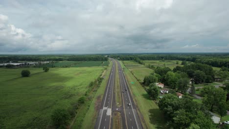 Aerial-drone-forward-moving-shot-over-two-way-expressway-beside-two-lakes-on-a-cloudy-day