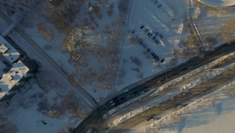 Luftdrohnenaufnahmen-Fliegen-Direkt-über-Eine-Große-Autobahn,-Die-Im-Winter-Durch-Eine-Städtische-Stadt-Fährt,-Die-Mit-Funkelndem-Weißem-Schnee-Bedeckt-Ist