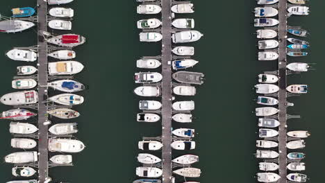 Aerial-view-directly-above-motor-boats-and-luxury-sailing-yachts-moored-in-a-marina