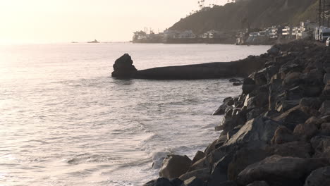 Rocky-stone-shoreline-edge-of-Big-Rock-Malibu-at-golden-hour,-next-to-the-highway-road