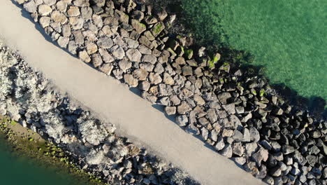 Aerial-flight-above-a-stone-pier-in-clear-turquoise-water