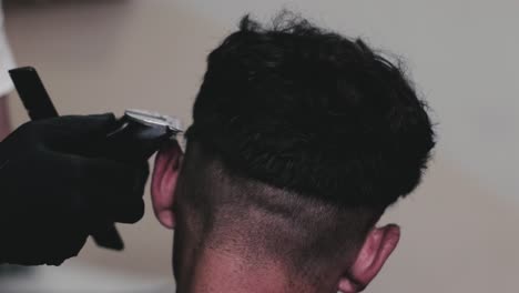 Barber-using-electric-clippers-to-cut-shot-the-hair-of-a-male-client-in-his-barbershop
