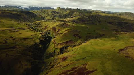 Aerial-panoramic-landscape-view-of-a-river-flowing-in-a-mountain-canyon,-in-Iceland