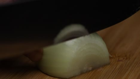 Slow-motion-close-up-shot-as-slicing-an-onion-on-a-wooden-desk-with-a-big-sharp-knife
