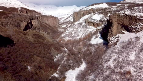 Flying-above-a-hiking-trail-at-the-bottom-of-a-rugged-canyon-with-cliffs-all-around-during-winter