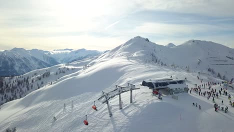 Toma-De-Dron-De-4k-De-Un-Remonte-En-Una-Montaña-Nevada-Perfecta-Con-Gente-Deportes-De-Invierno-Flachau,-Austria