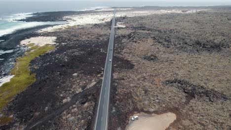 Aerial-view-of-straight-road-and-moving-cars-in-volcanic-coastline