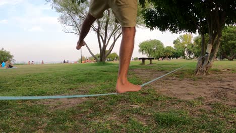 Close-up-legs-balancing-on-slack-line-in-park-outdoors-between-trees