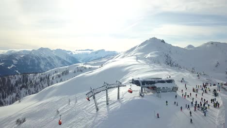 Vista-Aérea-De-Drones-De-Un-Remonte-En-La-Cima-De-Una-Montaña-Nevada-Con-Gente-En-Deportes-De-Invierno-Flachau,-Austria