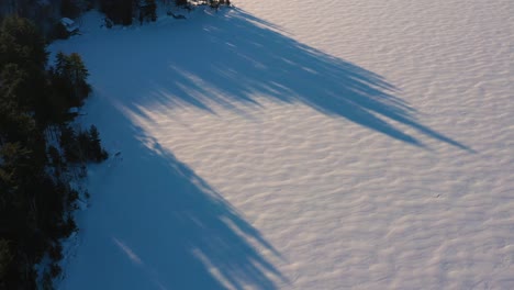 Luftaufnahme-Von-Der-Schneebedeckten-Oberfläche-Eines-Sees,-Um-Lager-Und-Einen-Berg-Mit-Einem-Linseneffekt-Zu-Enthüllen