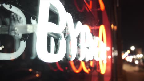 Close-up-defocused-pedestal-shot-of-a-neon-sign-at-night,-side-view