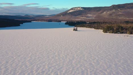 Aerial-PUSH-in-towards-small-wooded-island-in-a-frozen-northern-lake-in-Maine