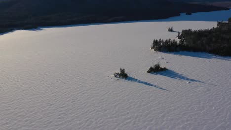 Aerial-Slide-looking-down-at-two-islands-in-a-frozen-lake-with-long-shadows