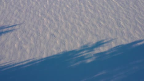 Aerial-TOPDOWN-flying-sideways-over-shadows-and-patterns-in-the-fresh-snow