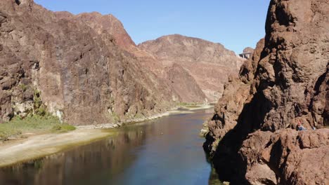 Aerial-view-of-people-sitting-on-cliffs-watching-rafts-on-the-Colorado-river---ascending,-drone-shot