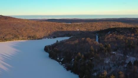 Fliegen-über-Einem-Verschneiten-Wald-In-Richtung-Eines-Eisenbahnbocks-Im-Norden-Von-Maine-Bei-Sonnenuntergang
